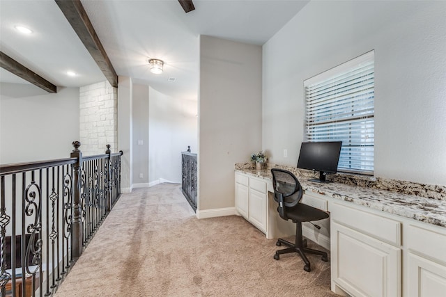 office space featuring light colored carpet, beam ceiling, built in study area, and baseboards