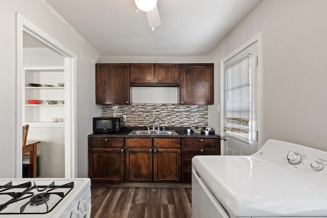 kitchen featuring black microwave, dark wood-type flooring, a sink, washer / clothes dryer, and dark countertops