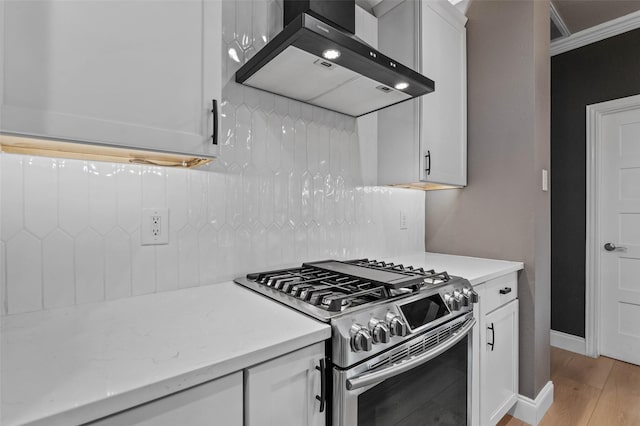 kitchen featuring light wood-style floors, white cabinetry, wall chimney exhaust hood, and gas range