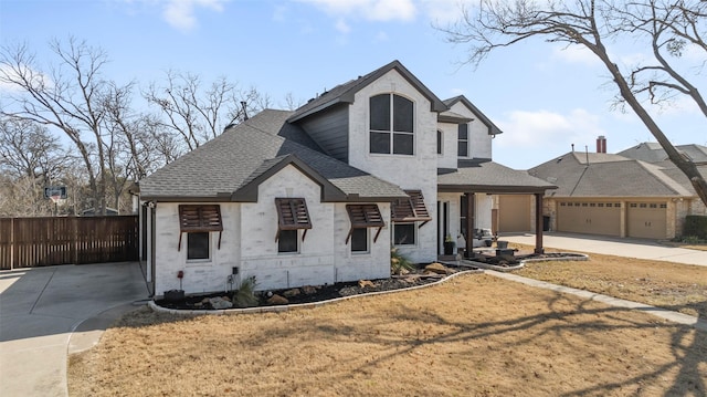 view of front of property featuring roof with shingles, fence, a garage, stone siding, and driveway