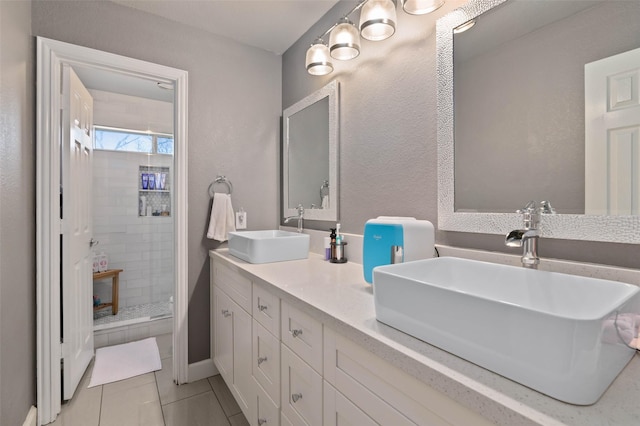 bathroom featuring double vanity, a sink, a shower stall, and tile patterned floors