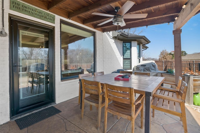 view of patio with grilling area, fence, outdoor dining area, and a ceiling fan