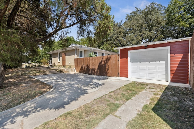 view of front of home with a garage, driveway, an outbuilding, and fence