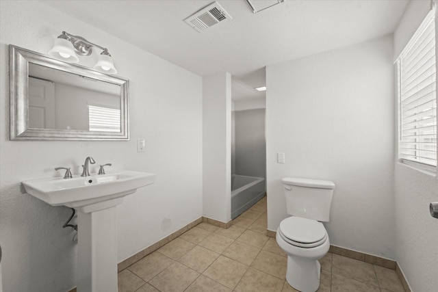 full bath featuring tile patterned flooring, toilet, visible vents, baseboards, and a tub