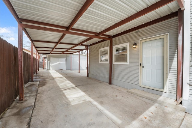 view of patio / terrace with an outbuilding, a carport, and fence