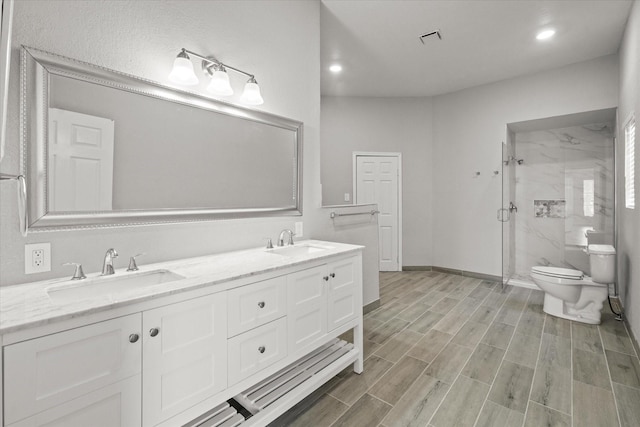 bathroom with toilet, a marble finish shower, a sink, and wood finish floors