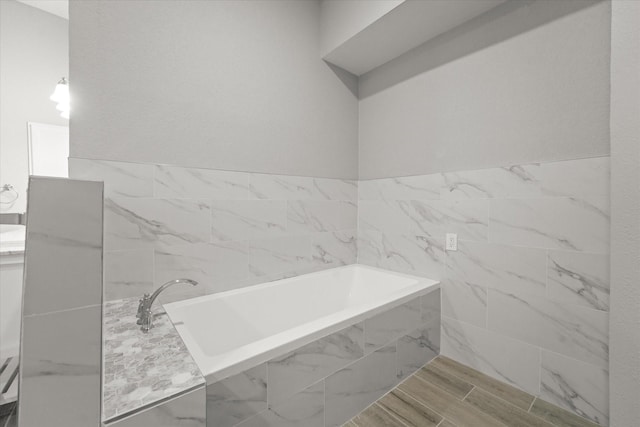 full bathroom featuring a garden tub, tile walls, and wood finished floors