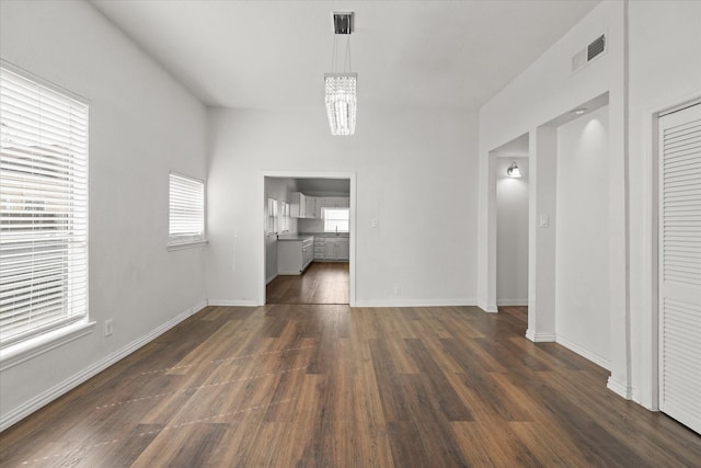 interior space featuring baseboards, visible vents, dark wood finished floors, and a chandelier