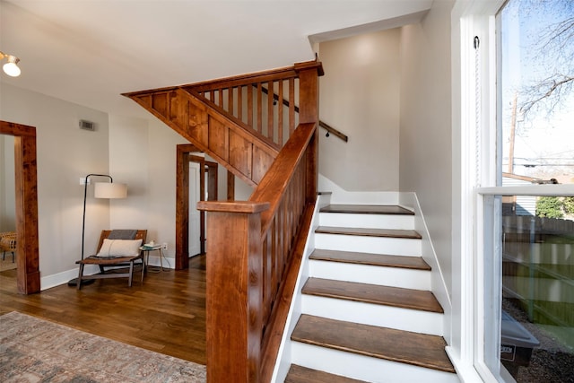 stairs with wood finished floors, visible vents, and baseboards