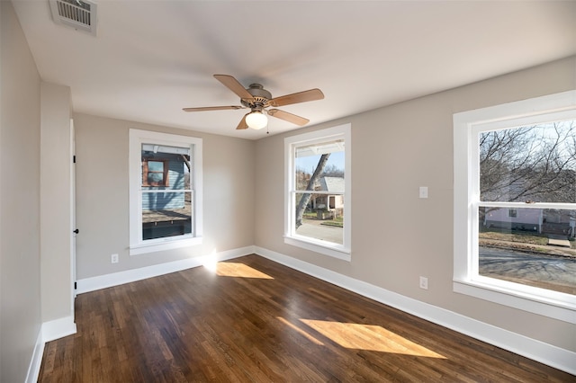 spare room featuring dark wood-style floors, baseboards, visible vents, and a ceiling fan