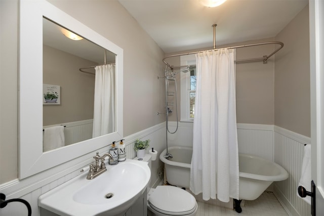 full bath with a wainscoted wall, shower / tub combo, a sink, and toilet