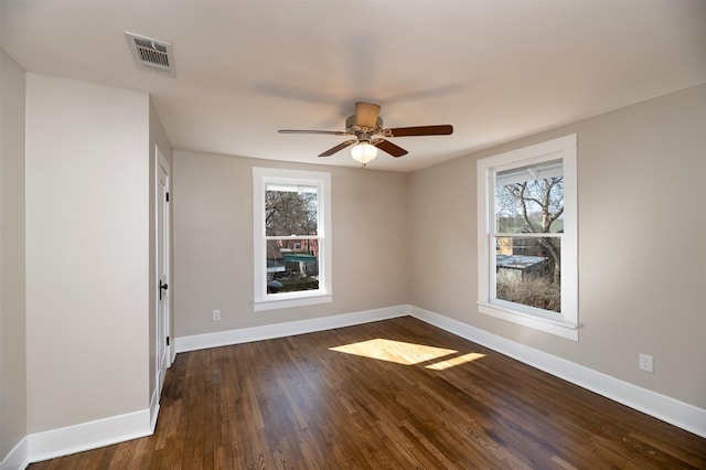 empty room featuring visible vents, dark wood finished floors, baseboards, and ceiling fan