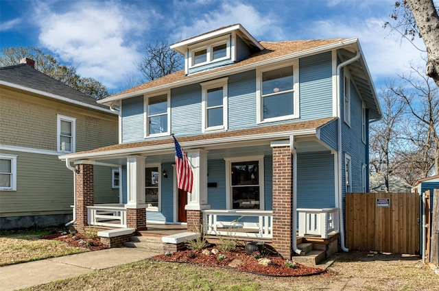 american foursquare style home with fence, a porch, and brick siding