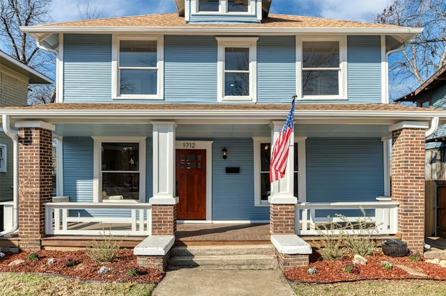 american foursquare style home with a porch and brick siding