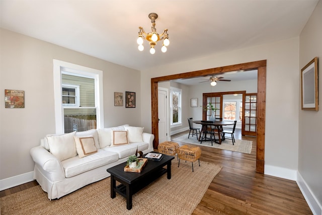 living room featuring a chandelier, baseboards, and wood finished floors