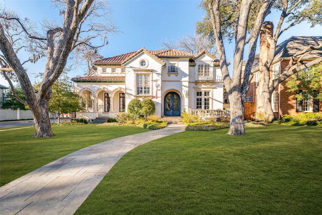 mediterranean / spanish-style house featuring a tiled roof, a front lawn, and stucco siding