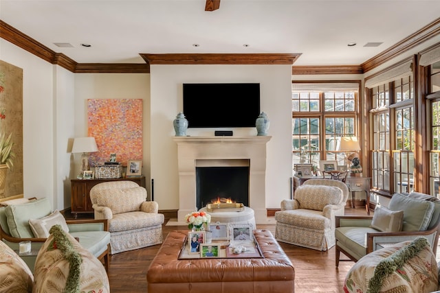 living room featuring crown molding, a lit fireplace, and wood finished floors