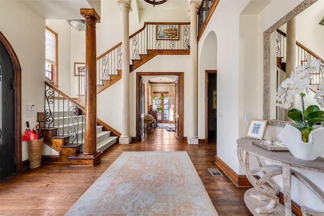 foyer with visible vents, arched walkways, dark wood-type flooring, a high ceiling, and ornate columns