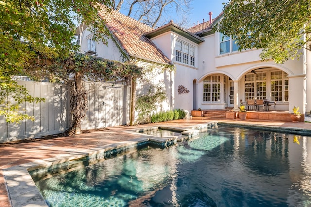 view of pool with a patio area, a pool with connected hot tub, fence, and french doors