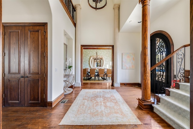 foyer entrance featuring stairs, dark wood finished floors, a towering ceiling, and visible vents