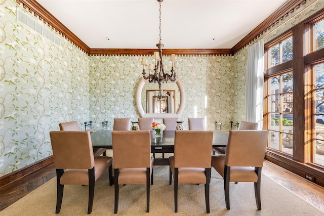 dining room with wallpapered walls, baseboards, wood finished floors, crown molding, and a chandelier