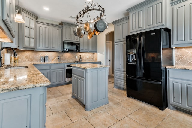 kitchen featuring arched walkways, black appliances, gray cabinets, and a sink