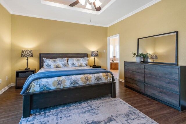 bedroom with ornamental molding, a tray ceiling, baseboards, and wood finished floors