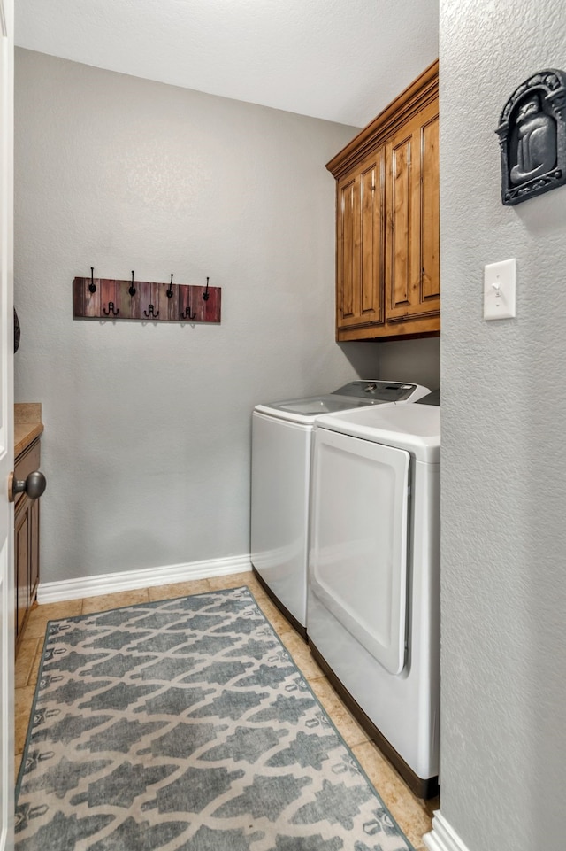 washroom featuring baseboards, cabinet space, and washer and dryer