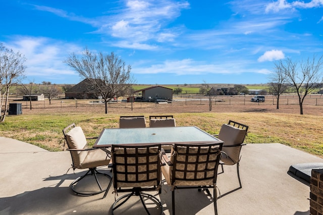 view of patio with outdoor dining area, a rural view, and fence