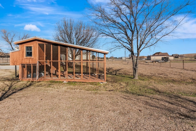 back of house featuring an outbuilding, fence, and exterior structure