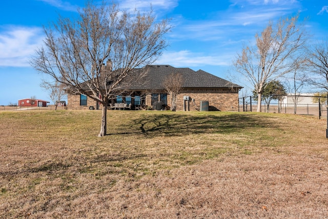 back of property with brick siding, a lawn, a chimney, and fence