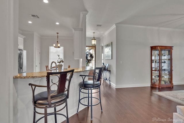 kitchen featuring dark wood-type flooring, light stone countertops, freestanding refrigerator, and white cabinetry