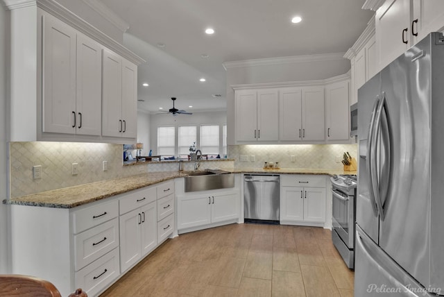 kitchen featuring white cabinetry, crown molding, appliances with stainless steel finishes, and a sink