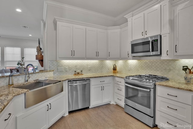 kitchen featuring stainless steel appliances, a sink, white cabinets, and crown molding