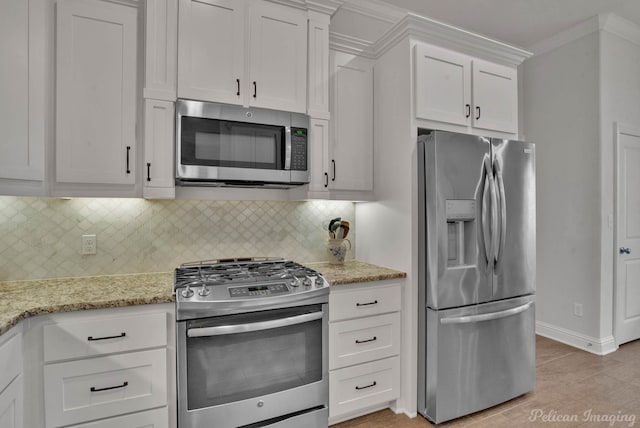 kitchen with baseboards, light stone counters, stainless steel appliances, white cabinetry, and backsplash