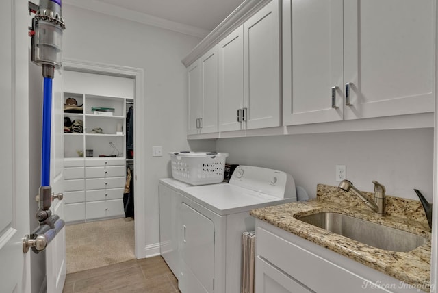 clothes washing area with ornamental molding, cabinet space, a sink, and washing machine and clothes dryer