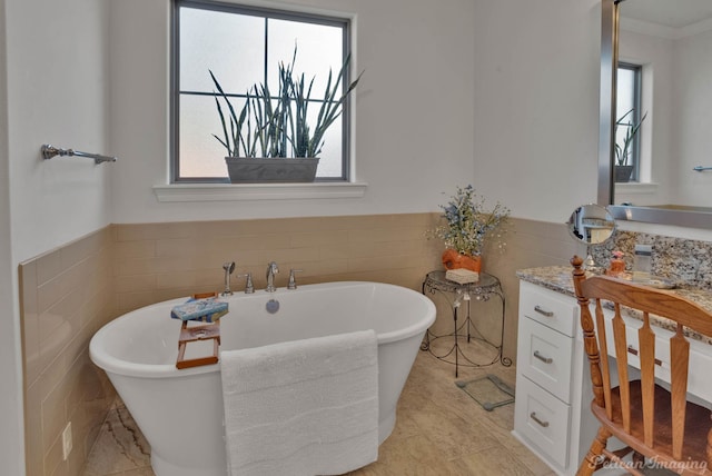 full bathroom with a wainscoted wall, tile walls, a wealth of natural light, and a soaking tub