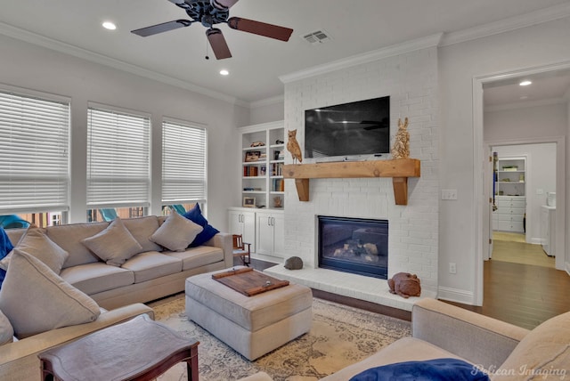 living room featuring crown molding, recessed lighting, visible vents, a brick fireplace, and wood finished floors