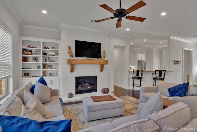 living room with a brick fireplace, crown molding, wood finished floors, and recessed lighting