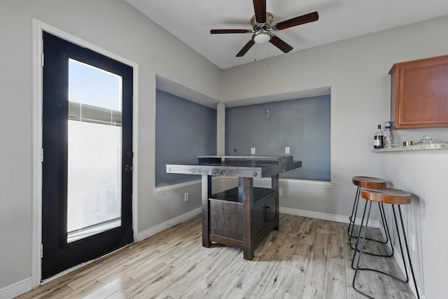 interior space featuring a ceiling fan, baseboards, and light wood finished floors