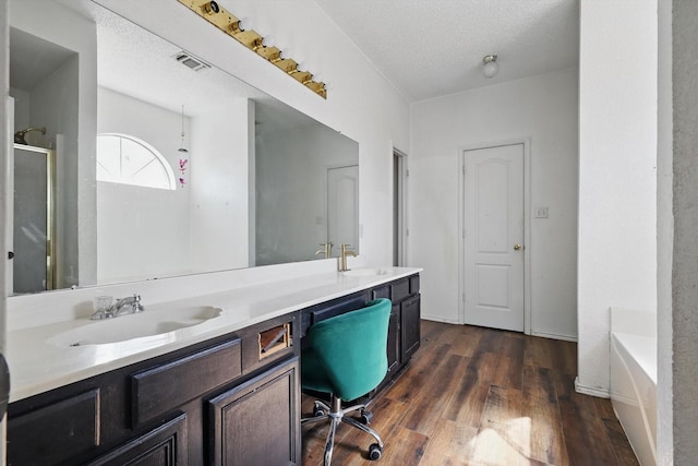 bathroom featuring double vanity, wood finished floors, a sink, and a shower stall