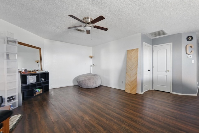 interior space with a ceiling fan, visible vents, a textured ceiling, and wood finished floors