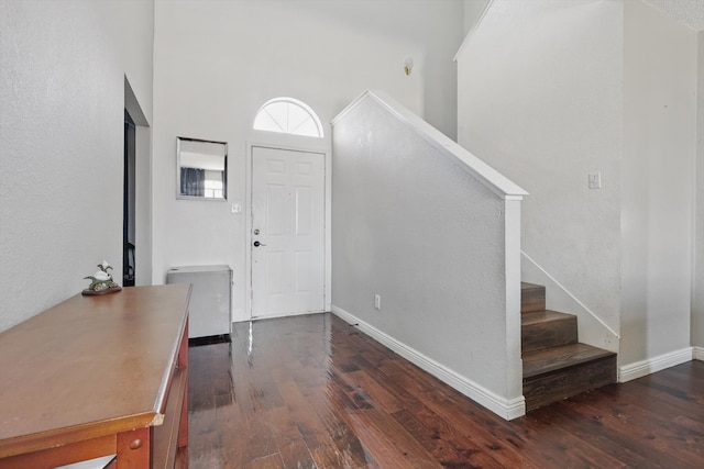 foyer featuring baseboards, dark wood finished floors, stairway, and a high ceiling