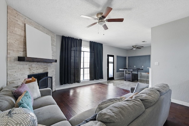 living room with a textured ceiling, a fireplace, wood finished floors, and a ceiling fan