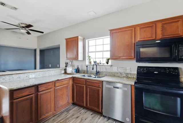 kitchen featuring a peninsula, a sink, visible vents, light stone countertops, and black appliances