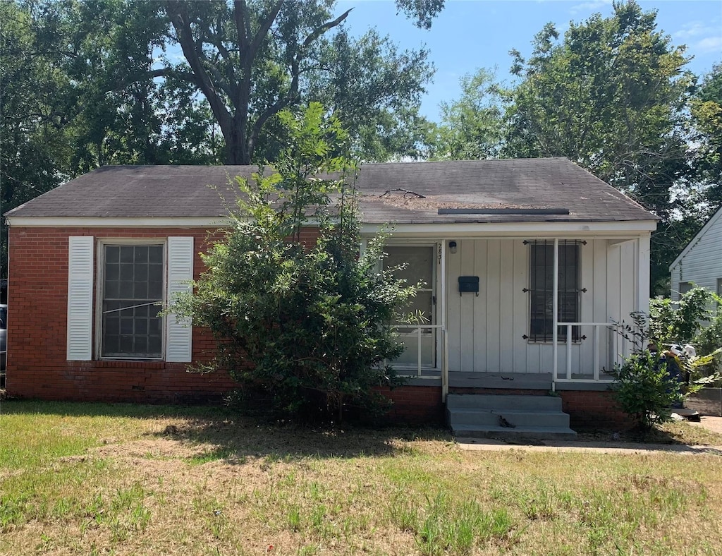 view of front of home with a front lawn, board and batten siding, and brick siding