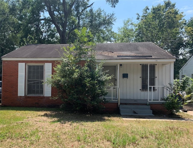 view of front of home with a front lawn, board and batten siding, and brick siding