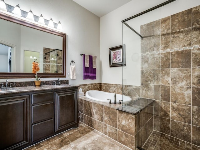 full bathroom with double vanity, a garden tub, a tile shower, and a sink