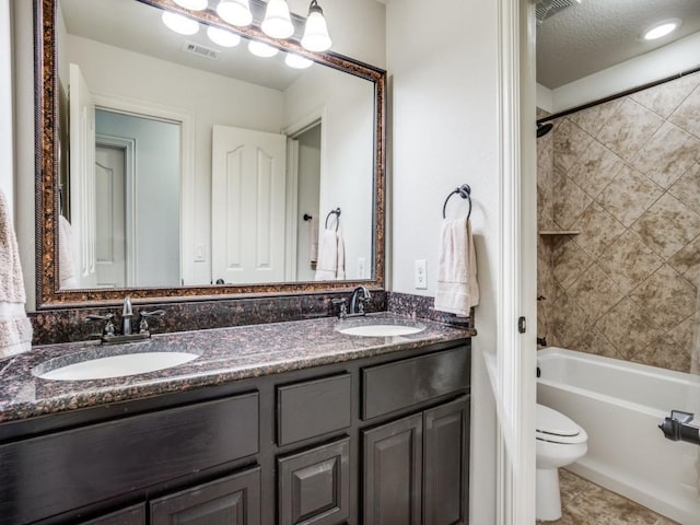 full bath featuring visible vents, double vanity, a sink, and toilet