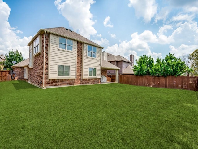 rear view of house with brick siding, a lawn, and a fenced backyard